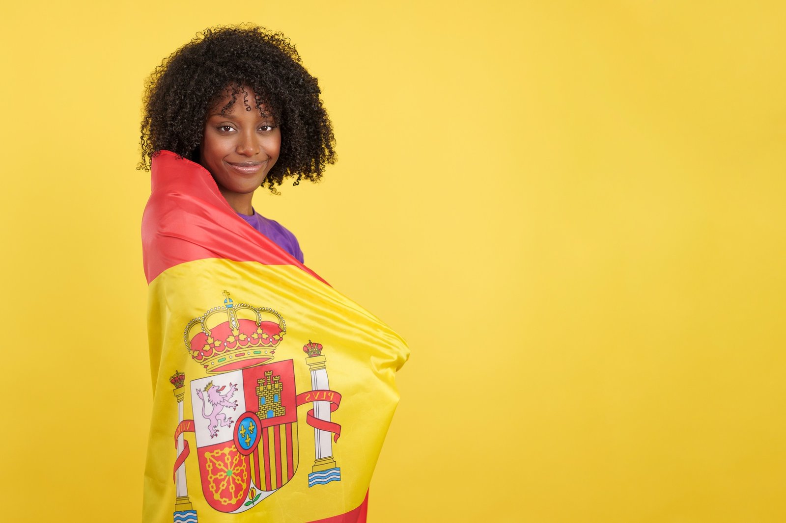 Migrant woman with afro hair wrapped with a Spanish flag